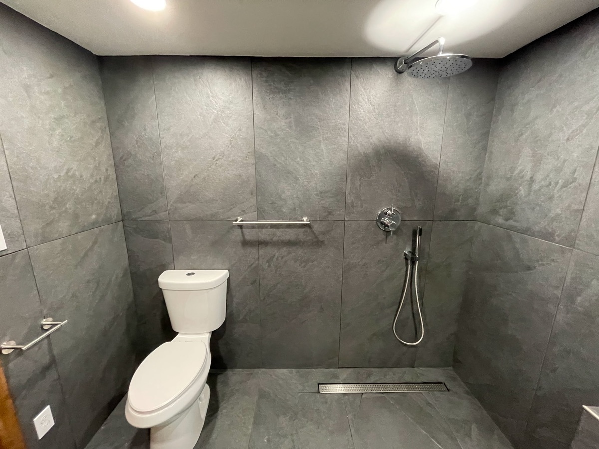 Finished bathroom with floor-to-ceiling slate tile and walk-in rainfall shower