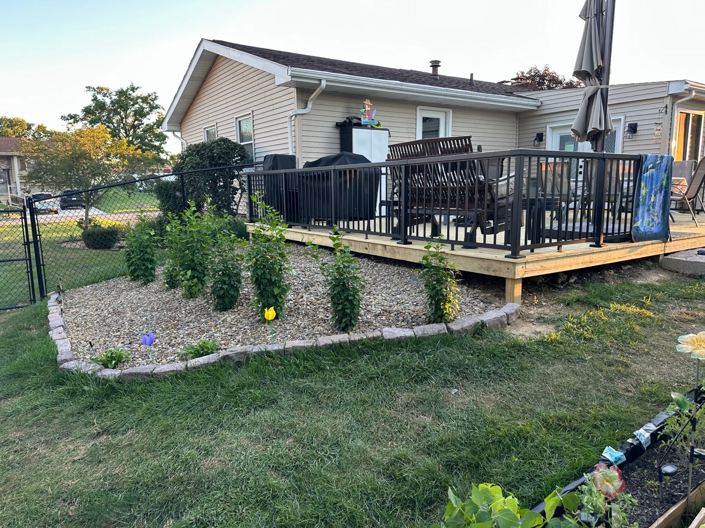New backyard deck with stone-edged river rock landscaping bed